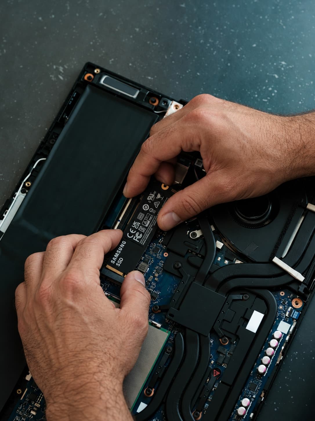 Mani di un tecnico durante la sostituzione di un SSD in un computer portatile